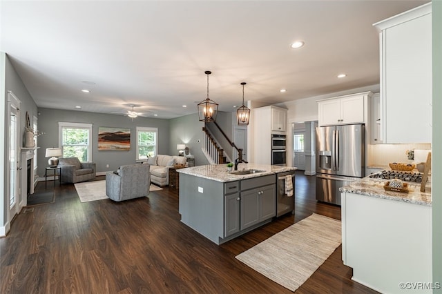 9377 Magnolia Blossom Rd, Ashland, VA 23005 - kitchen featuring stainless steel appliances, open floor plan, dark wood finished floors, an island with sink, and light stone counters