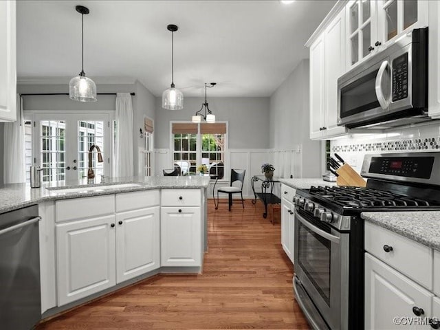 4416 Killiam Ct, Henrico, VA 23060 - kitchen with appliances with stainless steel finishes, light wood-style floors, white cabinetry, a wainscoted wall, and pendant lighting