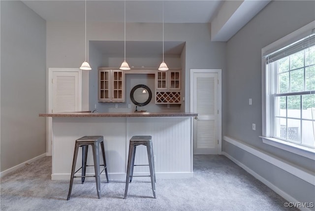 5501 Pine Needles Ter, Providence Forge, VA 23140 - kitchen featuring light carpet, glass insert cabinets, a breakfast bar, hanging light fixtures, and a center island