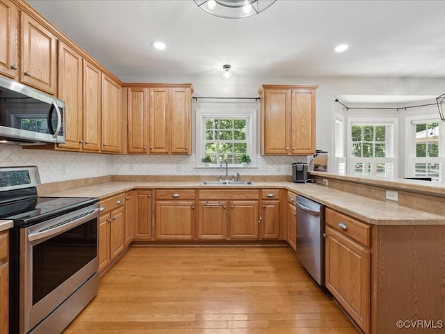 1960 Teal Ln, Powhatan, VA 23139 - kitchen with stainless steel appliances, a peninsula, light wood-type flooring, light countertops, and backsplash