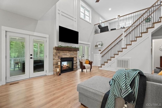 4788 Powhatan Lakes Rd, Powhatan, VA 23139 - living room featuring a towering ceiling, stairs, light wood-style floors, french doors, and a fireplace