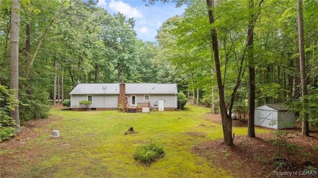 11192 Eventide Ln, Gloucester, VA 23061 - back of house featuring a storage unit, a yard, and a wooded view