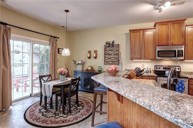 5669 Virginia Park Dr, Providence Forge, VA 23140 - kitchen featuring stainless steel appliances, brown cabinets, a breakfast bar, light stone counters, and decorative light fixtures