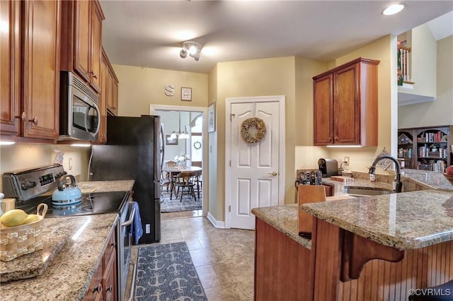 5669 Virginia Park Dr, Providence Forge, VA 23140 - kitchen with appliances with stainless steel finishes, a peninsula, brown cabinetry, a kitchen bar, and light stone counters