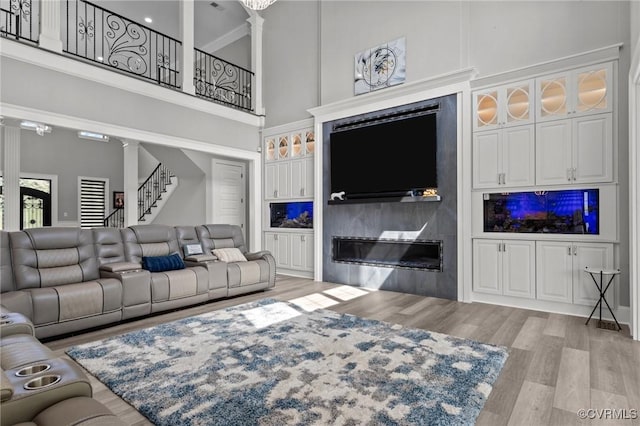 12313 Haybrook Ln, Henrico, VA 23059 - living area with ornate columns, a towering ceiling, wood finished floors, stairs, and a glass covered fireplace