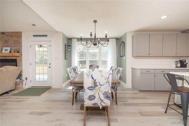 8851 Topeka Rd, Quinton, VA 23141 - dining space with light wood-style flooring, a chandelier, and a fireplace