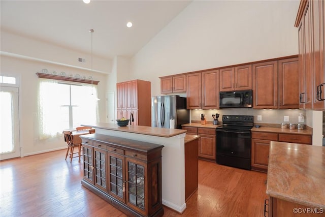 7822 James Blair Ln, New Kent, VA 23124 - kitchen featuring black appliances, high vaulted ceiling, brown cabinetry, light wood-style flooring, and light countertops
