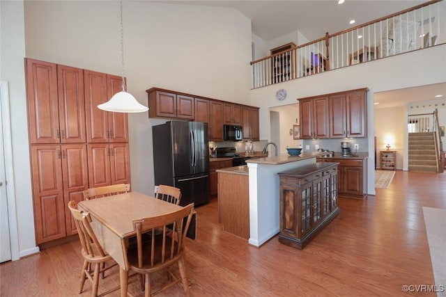 7822 James Blair Ln, New Kent, VA 23124 - kitchen with black appliances, wood finished floors, an island with sink, high vaulted ceiling, and pendant lighting