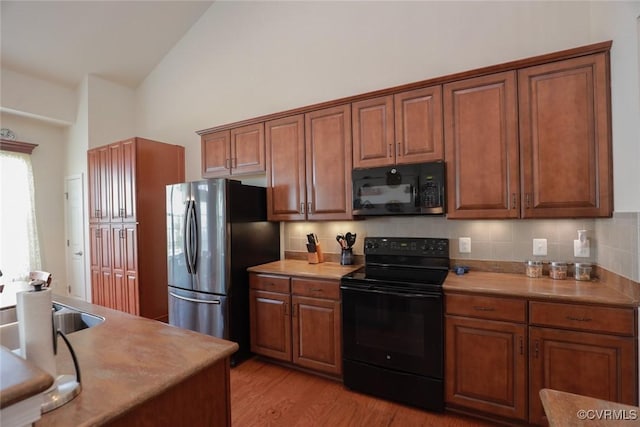 7822 James Blair Ln, New Kent, VA 23124 - kitchen featuring black appliances, brown cabinets, backsplash, light wood-type flooring, and high vaulted ceiling