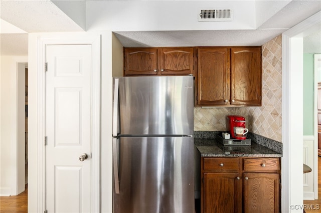 1917 Moonwind Pl, Henrico, VA 23238 - kitchen with freestanding refrigerator, brown cabinets, decorative backsplash, and dark stone counters