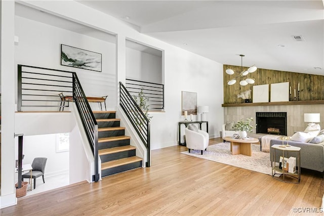 7418 Cherokee Rd, Richmond, VA 23225 - living area with light wood-type flooring, stairway, high vaulted ceiling, wood walls, and a fireplace