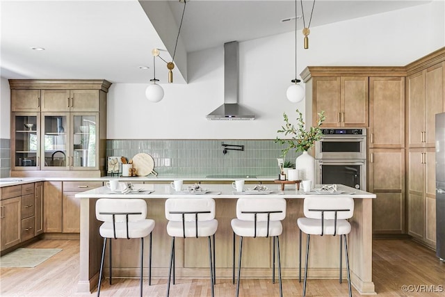 7418 Cherokee Rd, Richmond, VA 23225 - kitchen with wall chimney range hood, stainless steel double oven, light wood-style floors, and a breakfast bar area