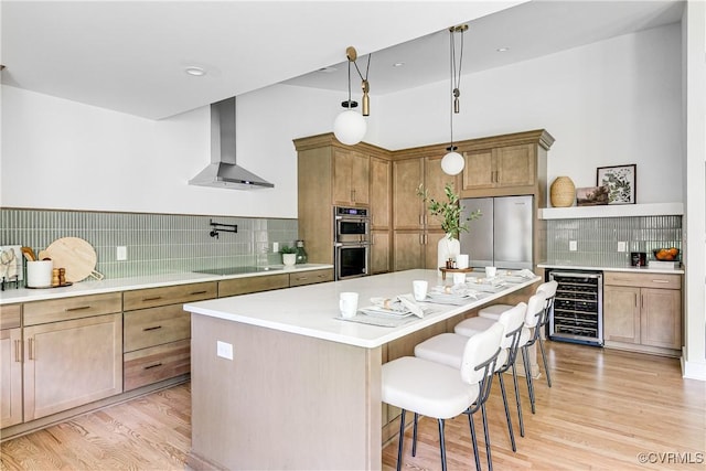 7418 Cherokee Rd, Richmond, VA 23225 - kitchen featuring wall chimney range hood, wine cooler, appliances with stainless steel finishes, backsplash, and light wood-type flooring