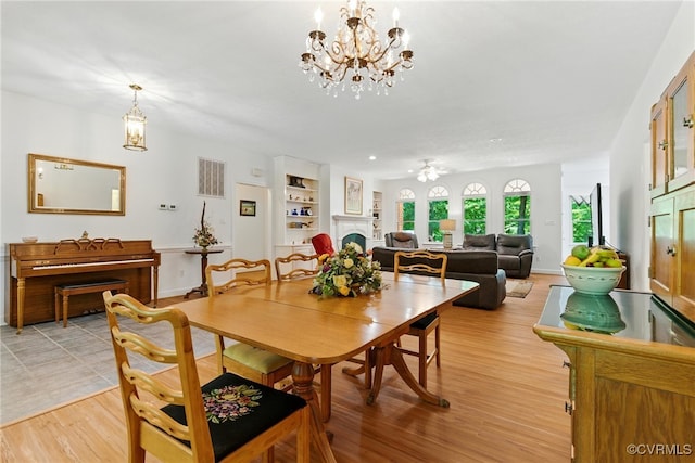 4800 Bailey Branch Ln, Quinton, VA 23141 - dining space featuring a fireplace, a chandelier, built in shelves, and light wood-type flooring