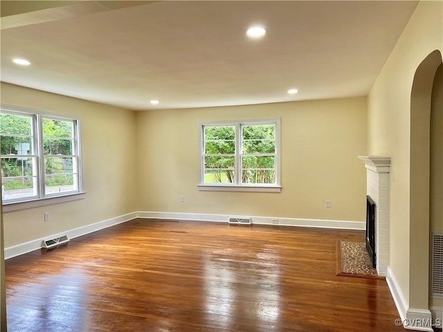 318 Youngs Rd, Petersburg, VA 23803 - unfurnished living room featuring wood finished floors, a brick fireplace, arched walkways, and recessed lighting
