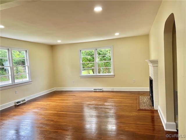 318 Youngs Rd, Petersburg, VA 23803 - unfurnished living room featuring wood-type flooring, arched walkways, a brick fireplace, and recessed lighting