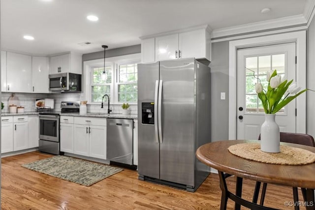 3519 Murchies Hill Rd, Richmond, VA 23234 - kitchen with appliances with stainless steel finishes, white cabinetry, light wood-type flooring, decorative backsplash, and ornamental molding