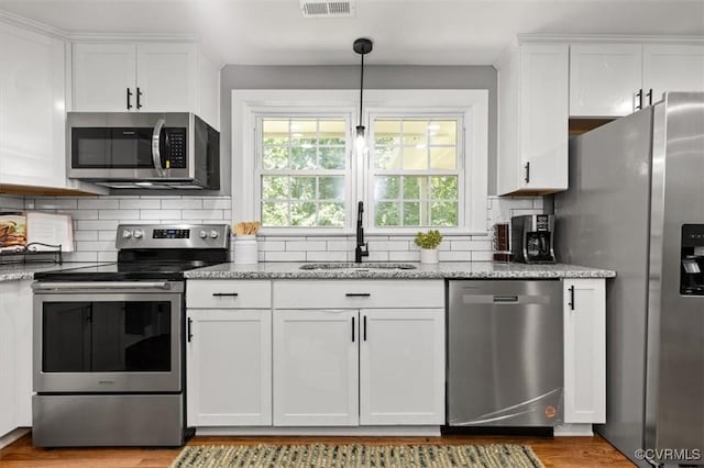 3519 Murchies Hill Rd, Richmond, VA 23234 - kitchen with stainless steel appliances, white cabinets, light wood-style flooring, and decorative backsplash