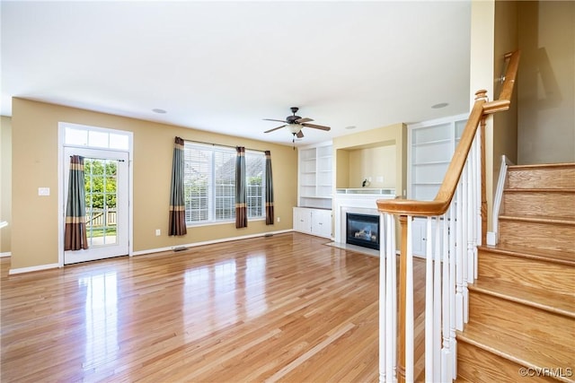 11420 Willows Green Way, Glen Allen, VA 23059 - unfurnished living room with light wood finished floors, a fireplace with flush hearth, ceiling fan, and stairway