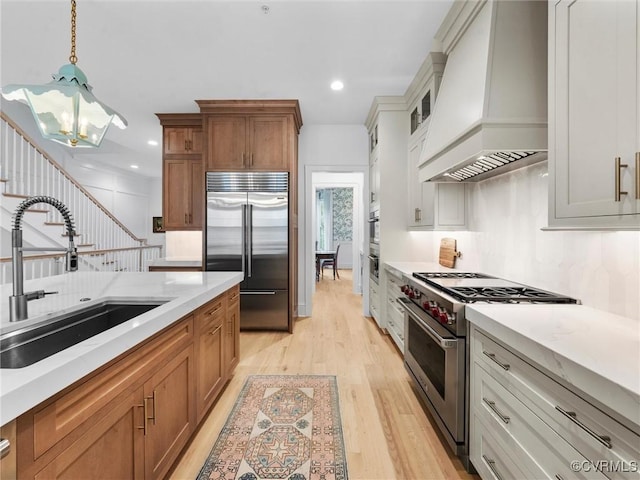 511 Libbie Ave Unit C, Richmond, VA 23226 - kitchen with premium appliances, premium range hood, light wood-style floors, a chandelier, and brown cabinetry