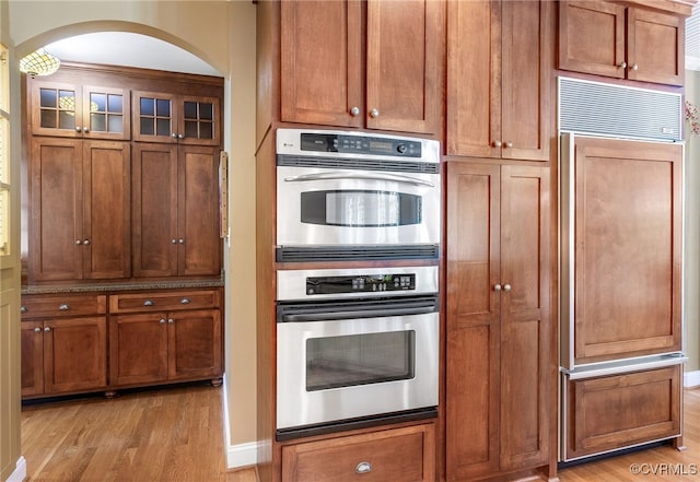 8707 Taylor Landing Pl, Chesterfield, VA 23838 - kitchen featuring paneled fridge, double oven, light wood-style flooring, arched walkways, and brown cabinets