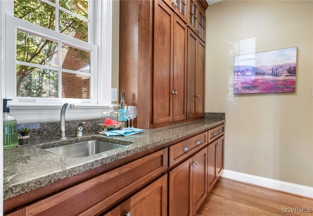 8707 Taylor Landing Pl, Chesterfield, VA 23838 - kitchen with brown cabinets, stone countertops, glass insert cabinets, and light wood-style flooring