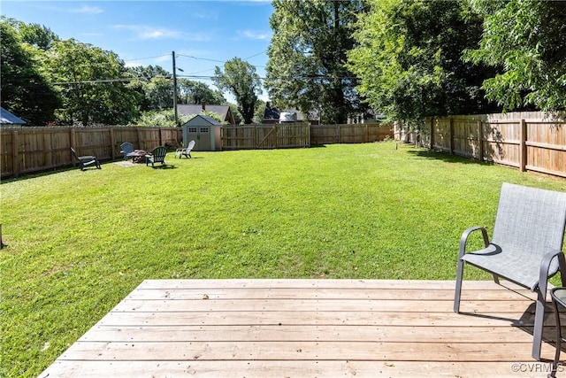 3712 Moody Ave, Richmond, VA 23225 - fenced backyard with a wooden deck, a storage unit, and a fire pit