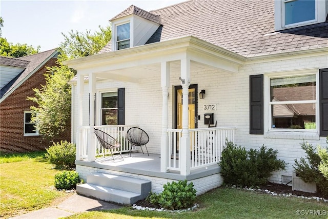 3712 Moody Ave, Richmond, VA 23225 - property entrance with covered porch, roof with shingles, brick siding, and a lawn