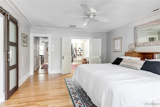 5005 Caledonia Rd, Richmond, VA 23225 - bedroom featuring light wood-style floors, a barn door, a spacious closet, and ceiling fan