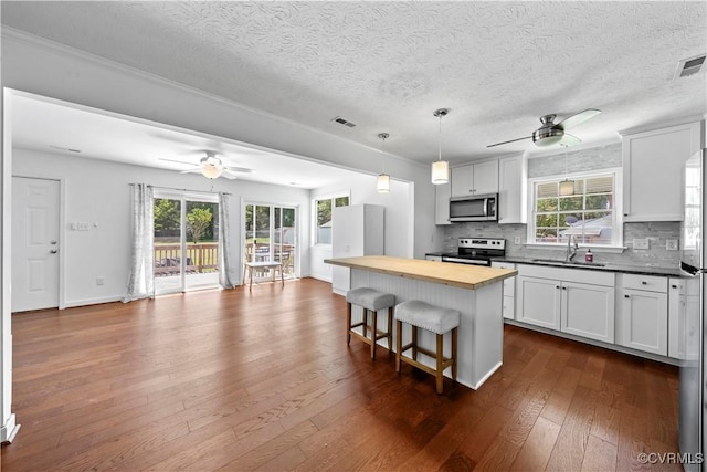 503 S Holly Ave, Henrico, VA 23075 - kitchen featuring appliances with stainless steel finishes, butcher block counters, a ceiling fan, a breakfast bar, and a textured ceiling