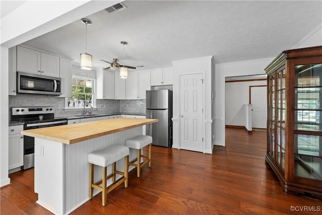 503 S Holly Ave, Henrico, VA 23075 - kitchen featuring appliances with stainless steel finishes, wood counters, decorative backsplash, a breakfast bar area, and a kitchen island