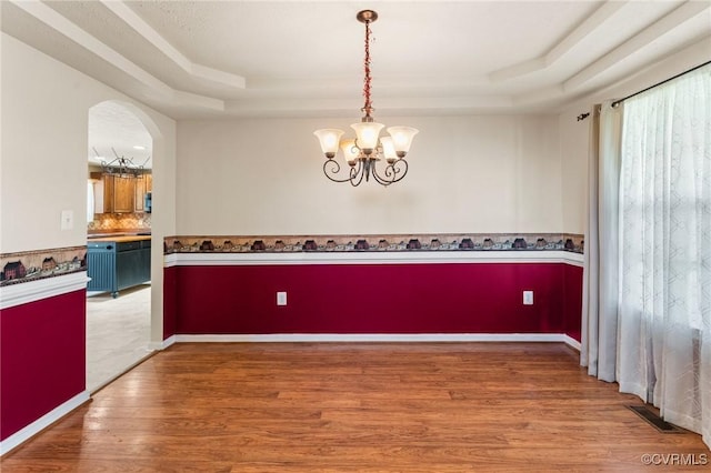 135 Hobbs Hole Ln, Tappahannock, VA 22560 - unfurnished dining area featuring a raised ceiling, a chandelier, wood finished floors, and arched walkways