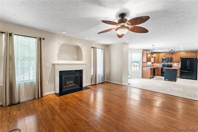 135 Hobbs Hole Ln, Tappahannock, VA 22560 - unfurnished living room featuring a textured ceiling, light wood finished floors, a glass covered fireplace, and ceiling fan