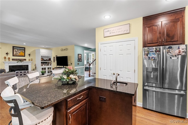 3105 Sapling Dr, Toano, VA 23168 - kitchen featuring stainless steel fridge with ice dispenser, dark stone counters, light wood-style floors, a fireplace, and a kitchen bar