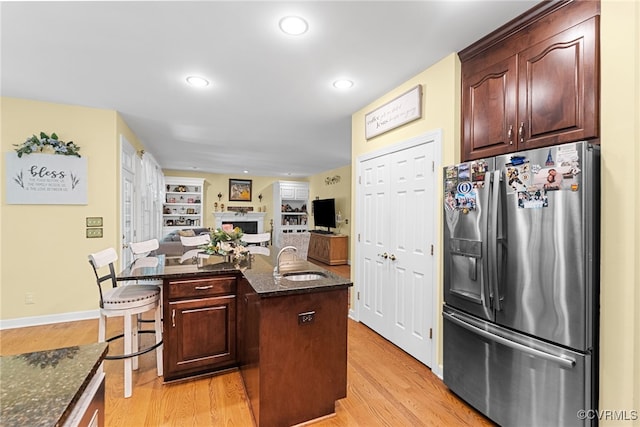 3105 Sapling Dr, Toano, VA 23168 - kitchen with stainless steel refrigerator with ice dispenser, light wood finished floors, a fireplace, an island with sink, and dark stone counters