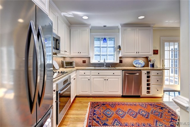 305 E Tazewells Way, Williamsburg, VA 23185 - kitchen with stainless steel appliances, light wood-style flooring, light stone countertops, white cabinetry, and crown molding