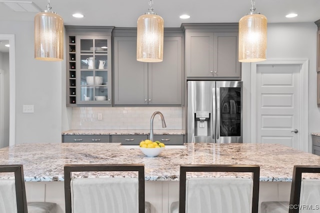 8300 Mckibben Dr, Chesterfield, VA 23838 - kitchen with stainless steel fridge with ice dispenser, gray cabinetry, decorative backsplash, light stone counters, and recessed lighting