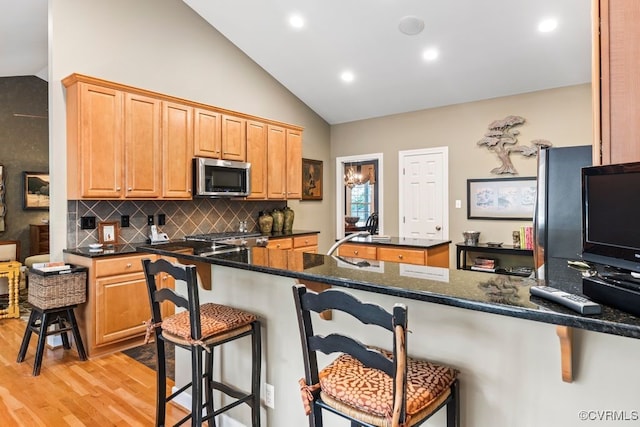 405 Elm Creek Dr, Manakin Sabot, VA 23103 - kitchen featuring stainless steel microwave, lofted ceiling, light wood finished floors, a breakfast bar, and decorative backsplash