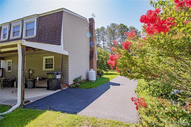 25014 James Ave, Dinwiddie, VA 23803 - view of side of home featuring a chimney, roof with shingles, and a patio
