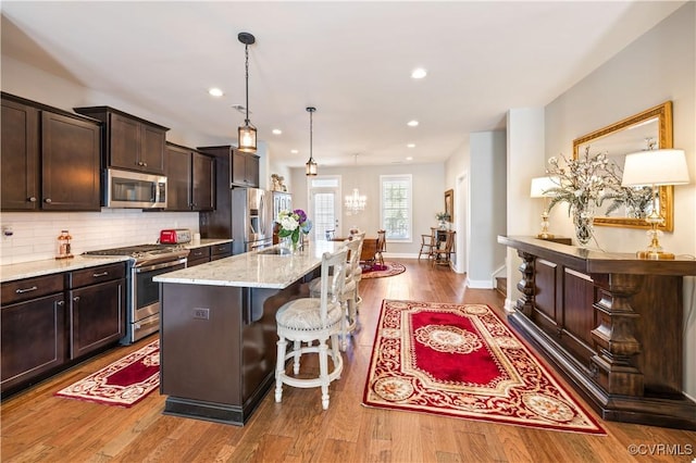 14432 Michaux Village Dr, Midlothian, VA 23113 - kitchen with stainless steel appliances, a kitchen bar, dark brown cabinetry, light stone counters, and a kitchen island with sink