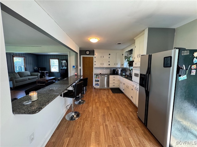7360 Ford Ave, Mechanicsville, VA 23111 - kitchen featuring appliances with stainless steel finishes, light wood-style floors, white cabinetry, backsplash, and a peninsula