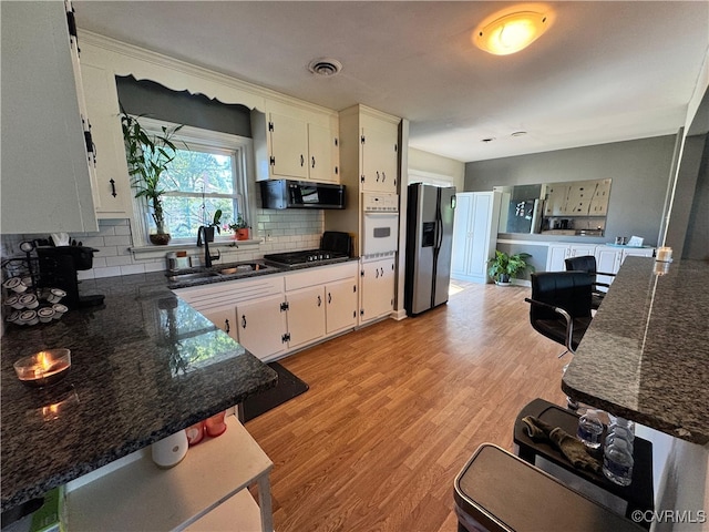 7360 Ford Ave, Mechanicsville, VA 23111 - kitchen featuring appliances with stainless steel finishes, light wood finished floors, backsplash, and white cabinets