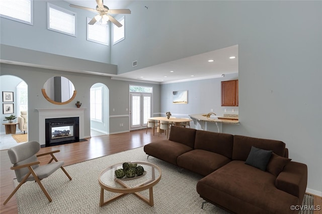 5027 Lewisetta Dr, Glen Allen, VA 23060 - living room with light wood-style flooring, a ceiling fan, a glass covered fireplace, a high ceiling, and recessed lighting