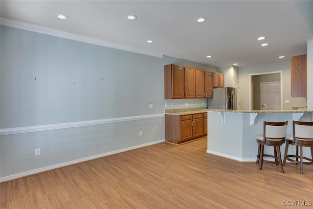 5027 Lewisetta Dr, Glen Allen, VA 23060 - kitchen featuring stainless steel fridge with ice dispenser, brown cabinets, a breakfast bar, light wood finished floors, and recessed lighting