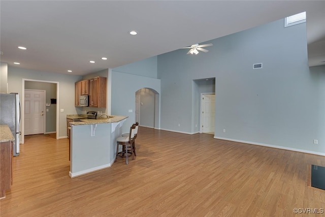 5027 Lewisetta Dr, Glen Allen, VA 23060 - kitchen featuring stainless steel appliances, arched walkways, ceiling fan, brown cabinetry, and light wood-style floors