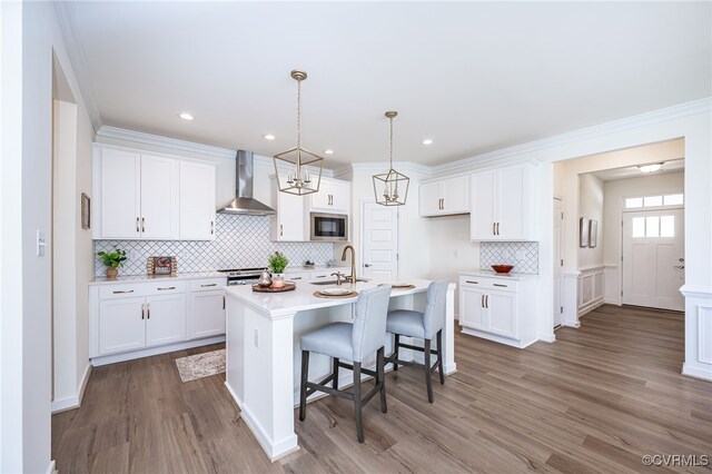 10698 Skippers St, Glen Allen, VA 23059 - kitchen with wall chimney range hood, stainless steel microwave, decorative backsplash, wood finished floors, and ornamental molding