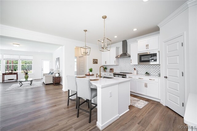 10698 Skippers St, Glen Allen, VA 23059 - kitchen with appliances with stainless steel finishes, wall chimney exhaust hood, a kitchen bar, wood finished floors, and recessed lighting