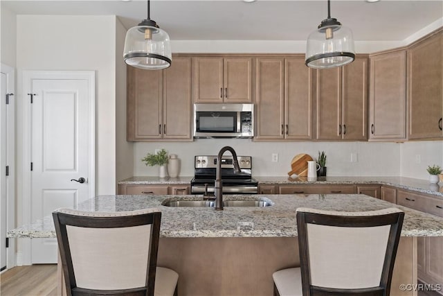 109 Axton Ln, Ashland, VA 23005 - kitchen featuring appliances with stainless steel finishes, a breakfast bar area, light stone counters, and decorative light fixtures