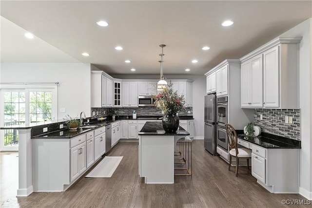6430 Arwen Mews, Moseley, VA 23120 - kitchen featuring appliances with stainless steel finishes, a breakfast bar area, decorative backsplash, white cabinetry, and a center island
