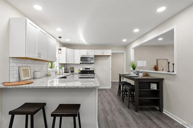 2718 Colgrave Rd, Chesterfield, VA 23112 - kitchen with stainless steel appliances, a peninsula, white cabinets, wood finished floors, and recessed lighting